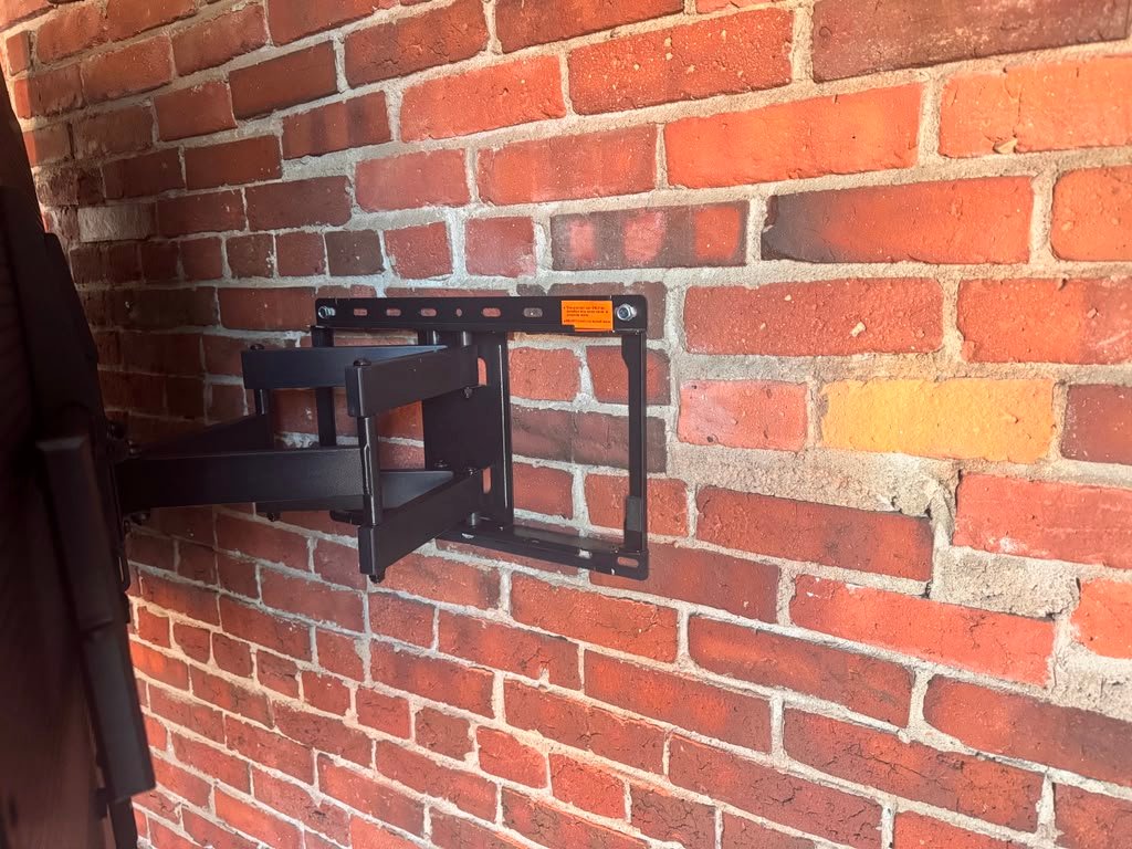TV swivel bracket mounted on brick wall